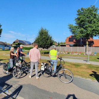 Die Tourteilnehmer*innen stehen mit ihren Fahrrädern vor dem Mehrgenerationenplatz in Strücklingen.